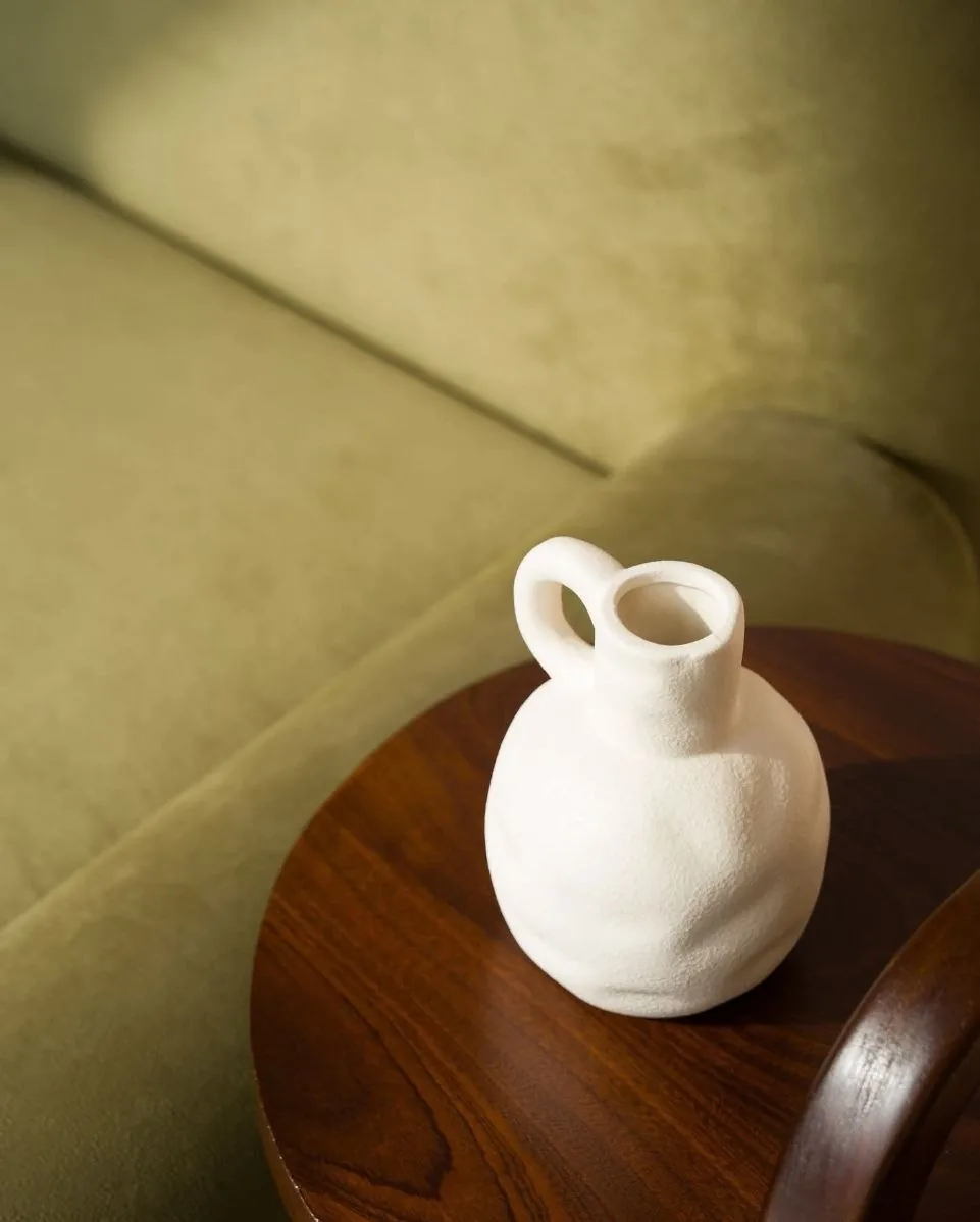 Vase blanc posé sur un guéridon en bois sombre