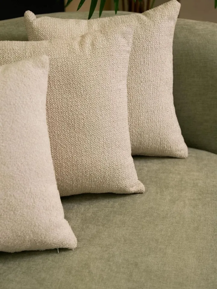 Coussins en bouclette sur un canapé sauge